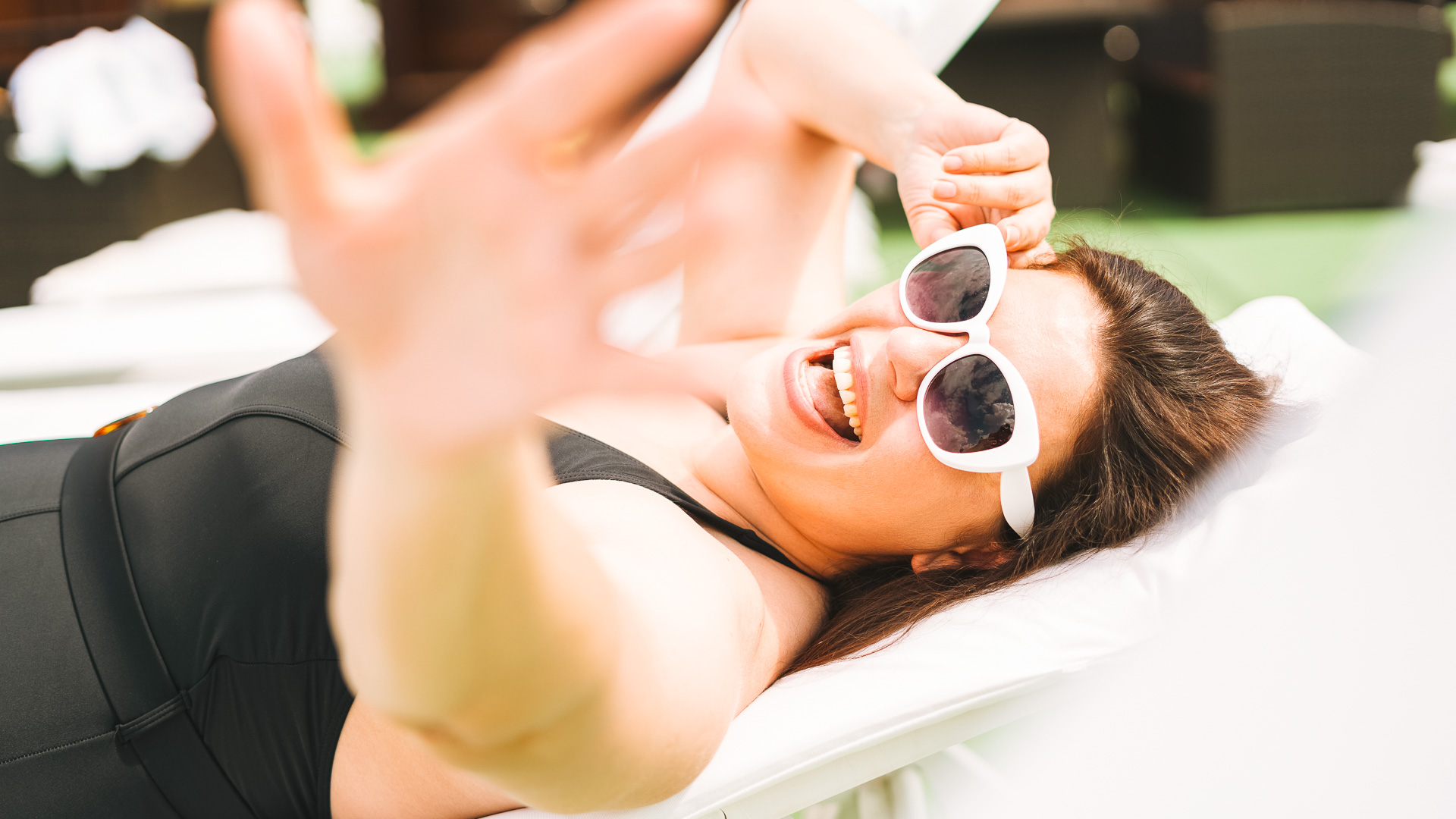 a woman lying on a lounge chair with her hands up