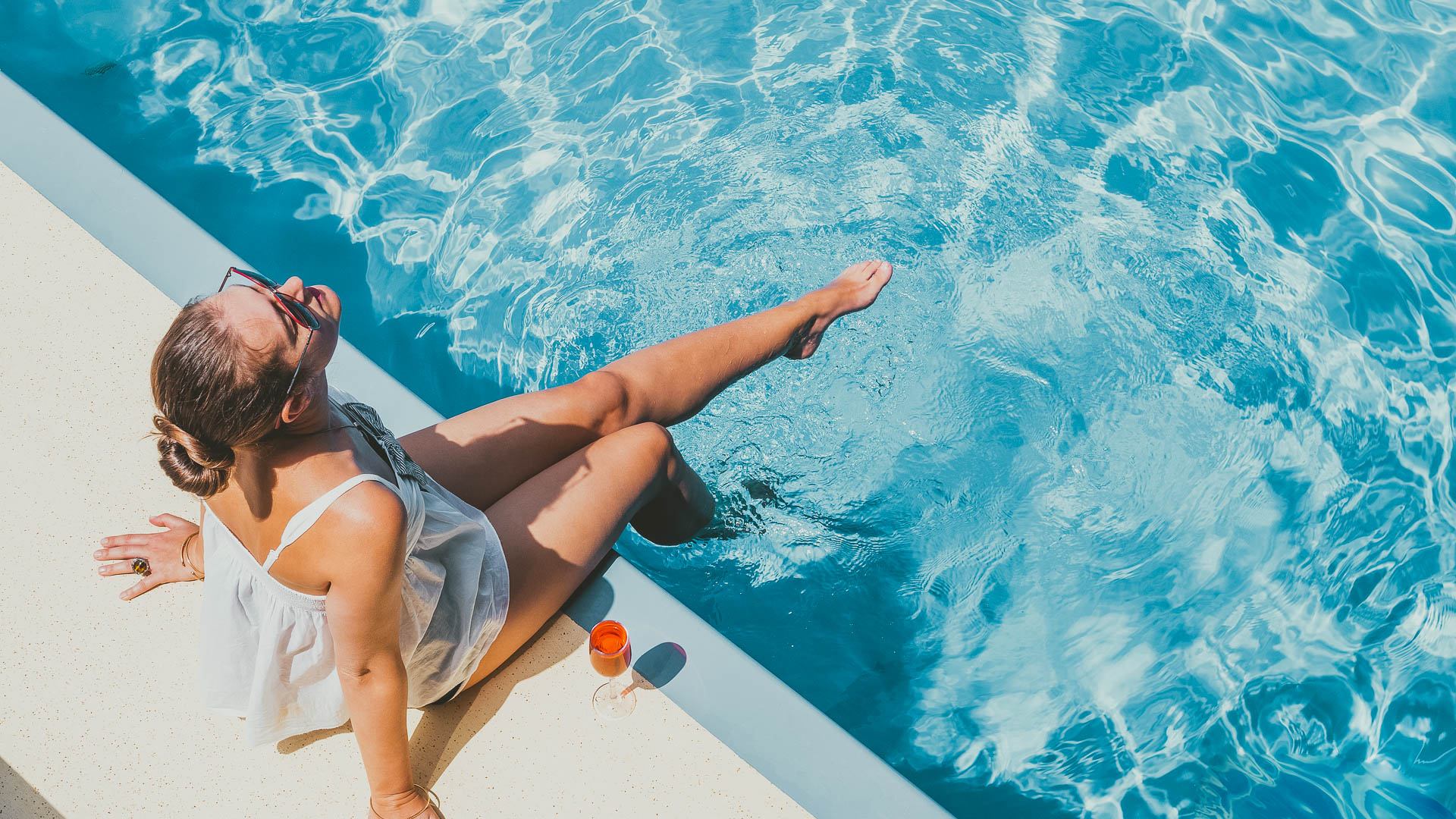 a woman sitting on edge of a pool