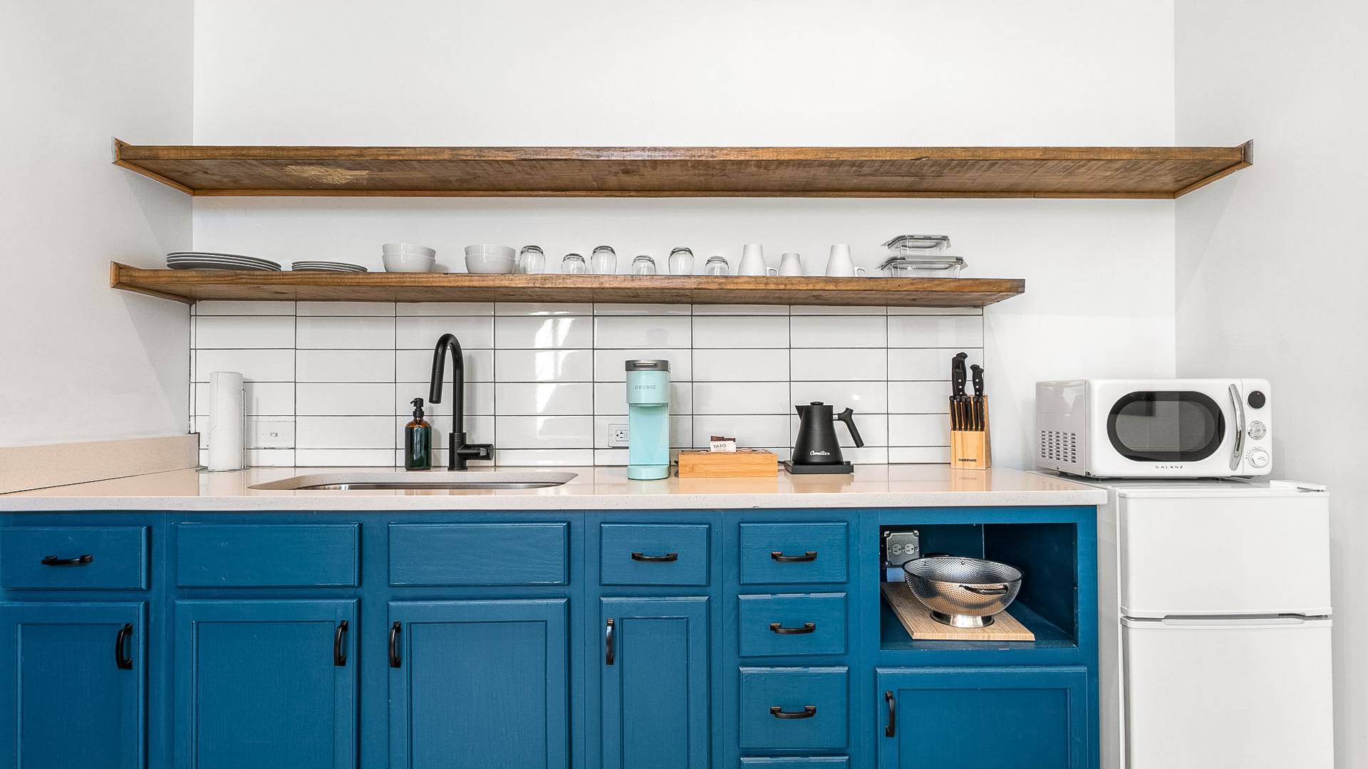 a kitchen with blue cabinets and white tile