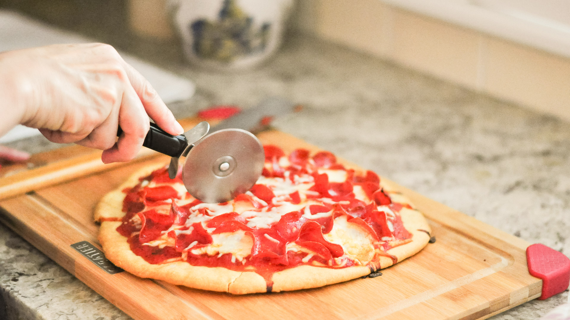 a pizza cutter cutting a pizza
