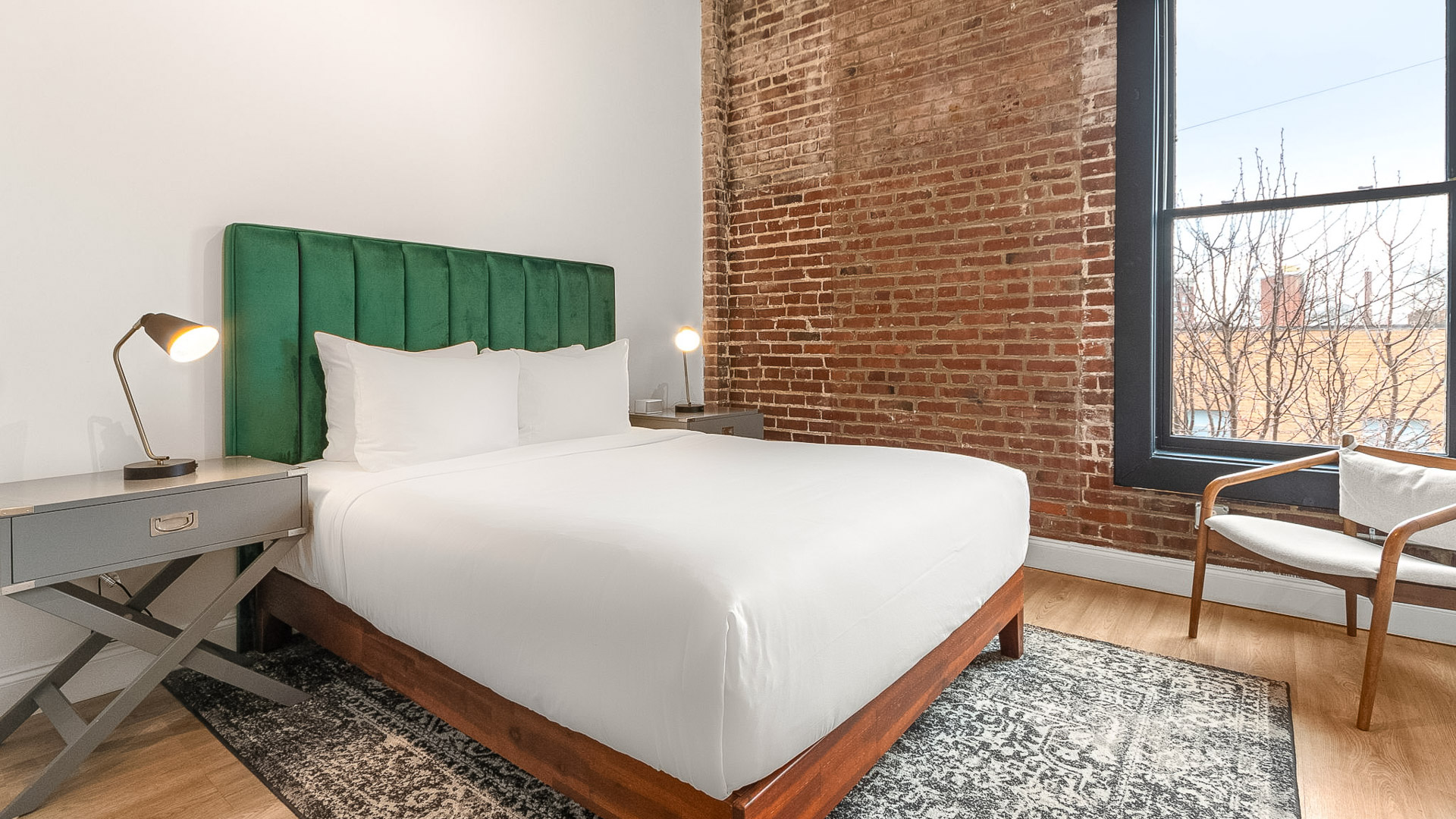a bed with a green headboard in a room with brick walls