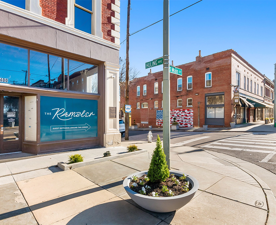 a street corner with a sign and a tree in a pot