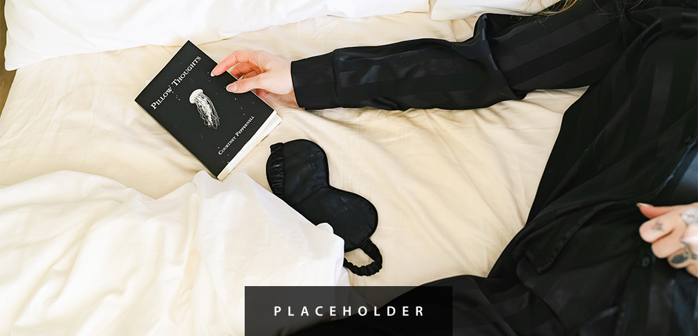 a hand holding a book next to a sleeping mask