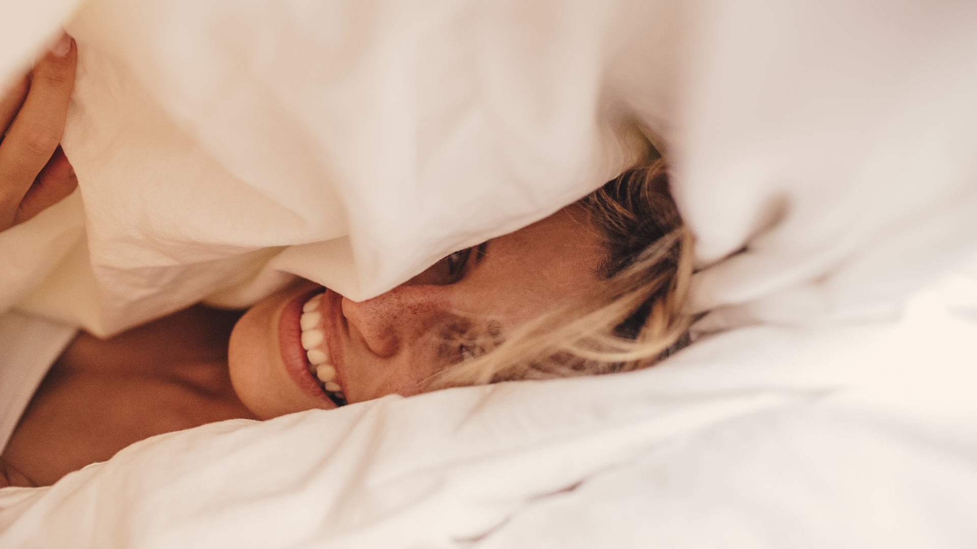 a woman lying under a blanket