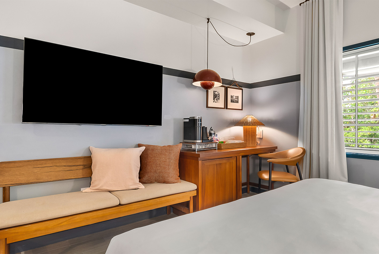 a room with a bed and a desk and a tv