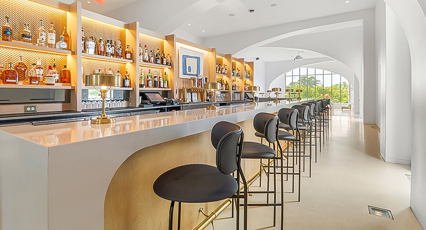 a bar with chairs and shelves of liquor