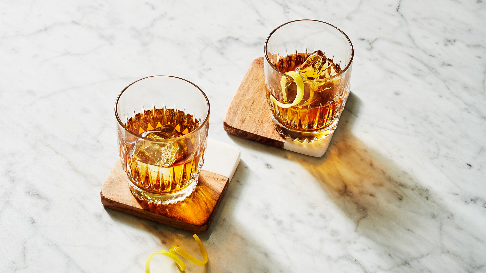 two glasses of alcohol on coasters