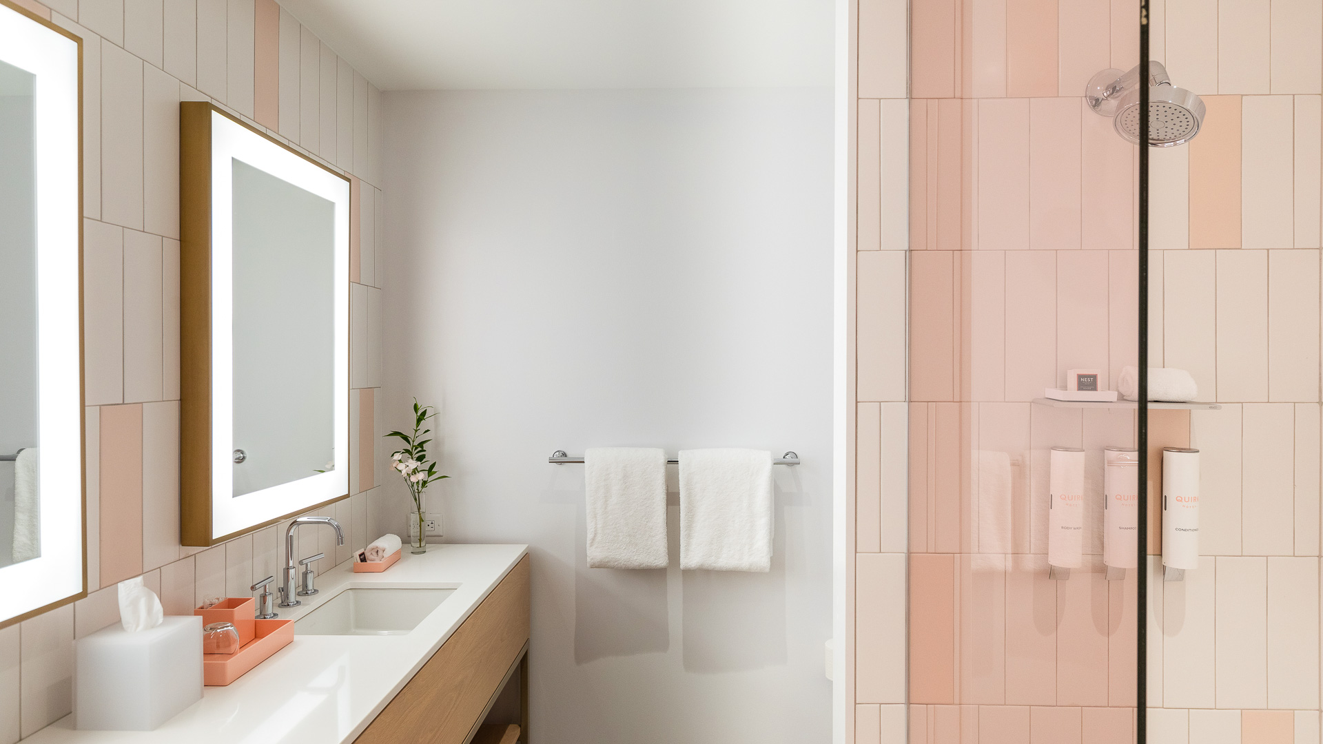 a bathroom with pink tile walls and white countertops