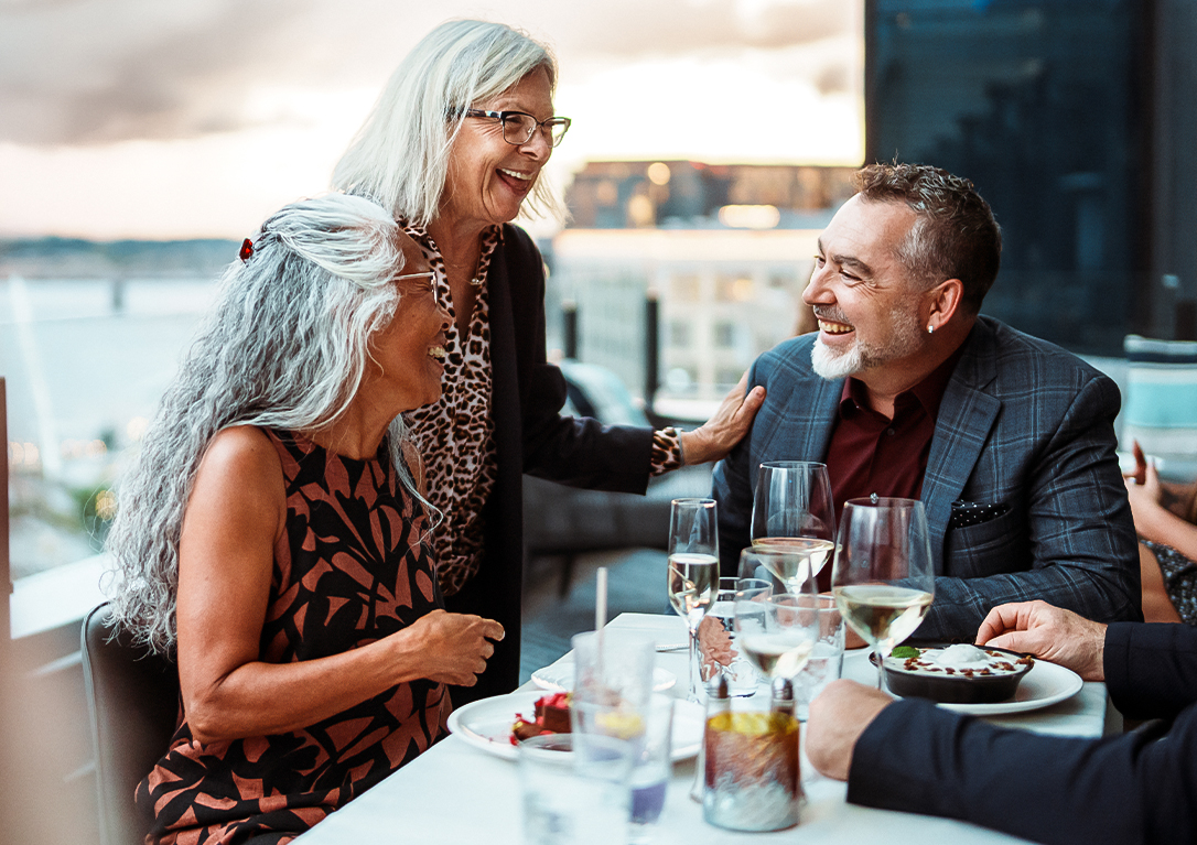 a group of people sitting at a table with food and drinks
