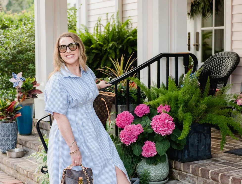 a woman in a blue dress standing on a brick porch