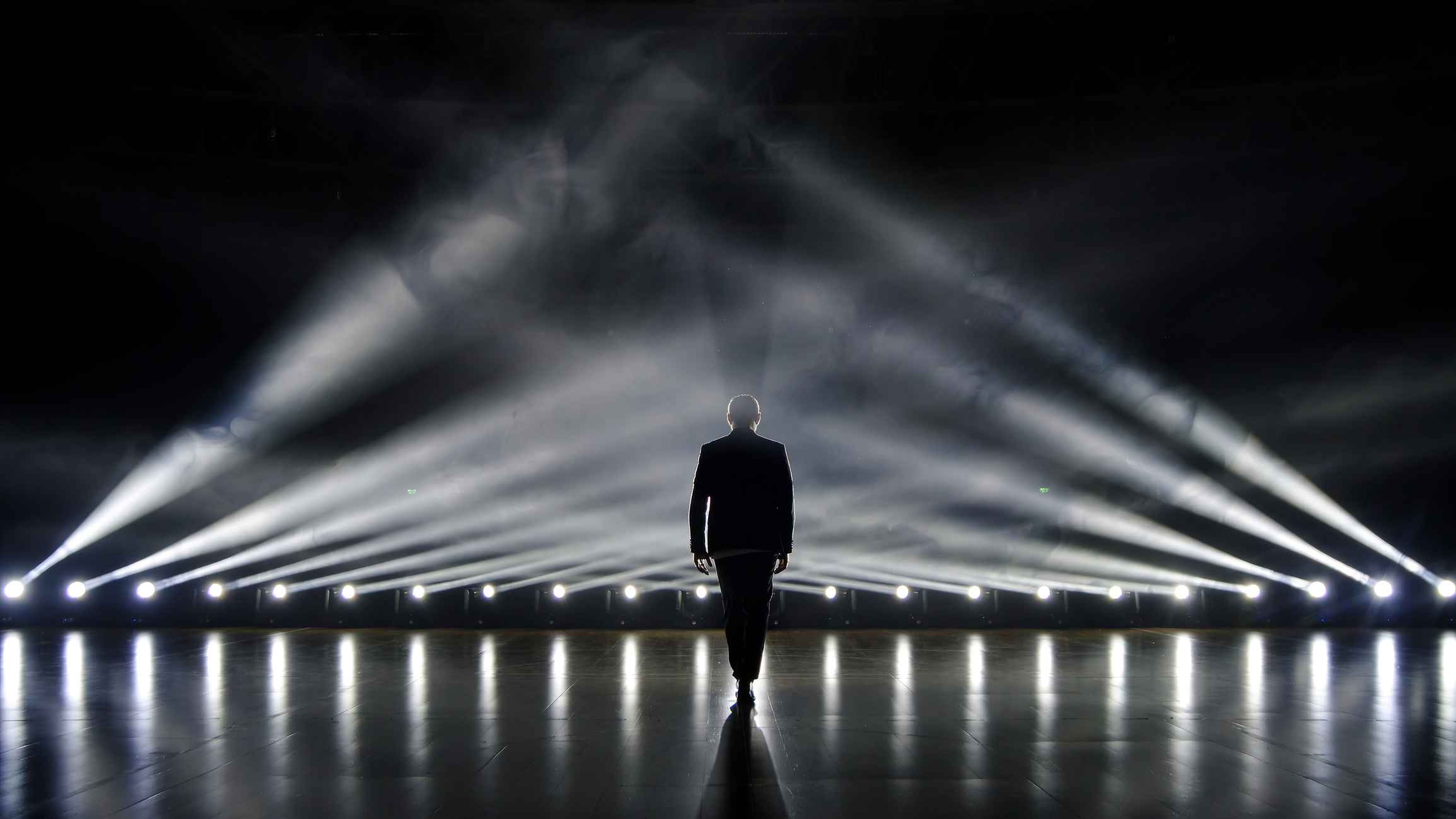 a man walking in front of a stage with lights
