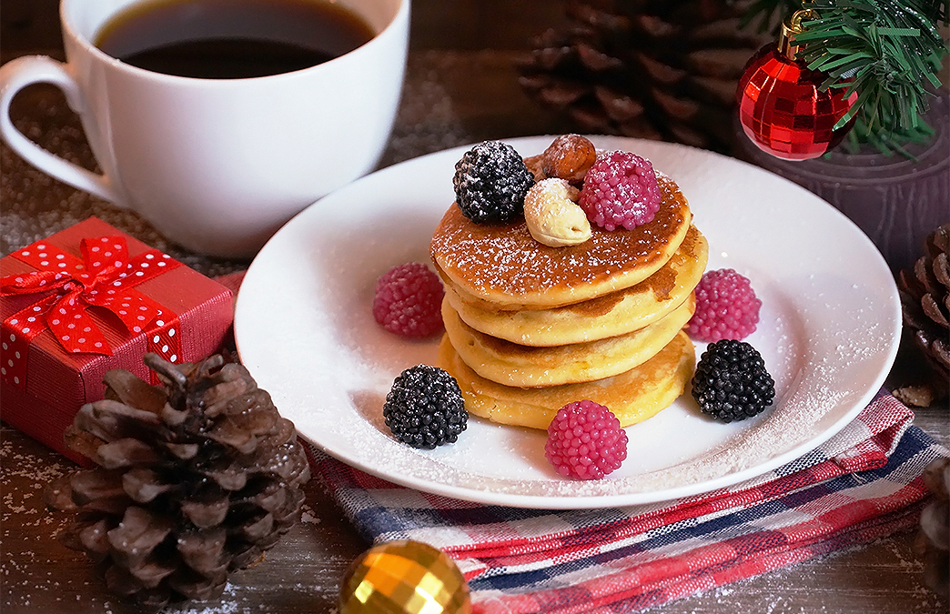 a stack of pancakes with berries and nuts on a plate
