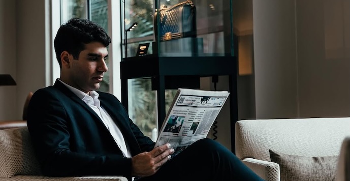 a man sitting in a chair reading a newspaper
