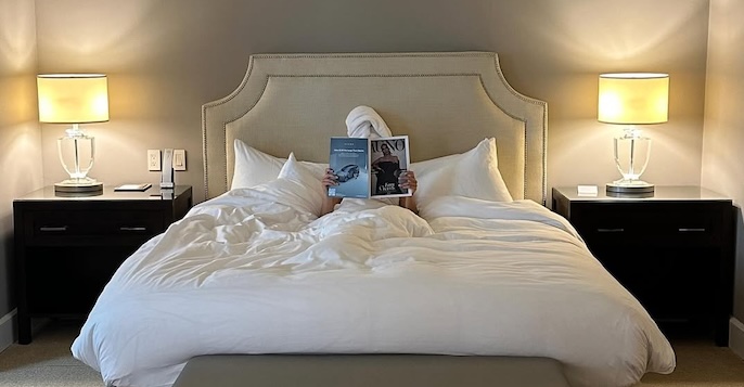 a person lying in a bed with a book