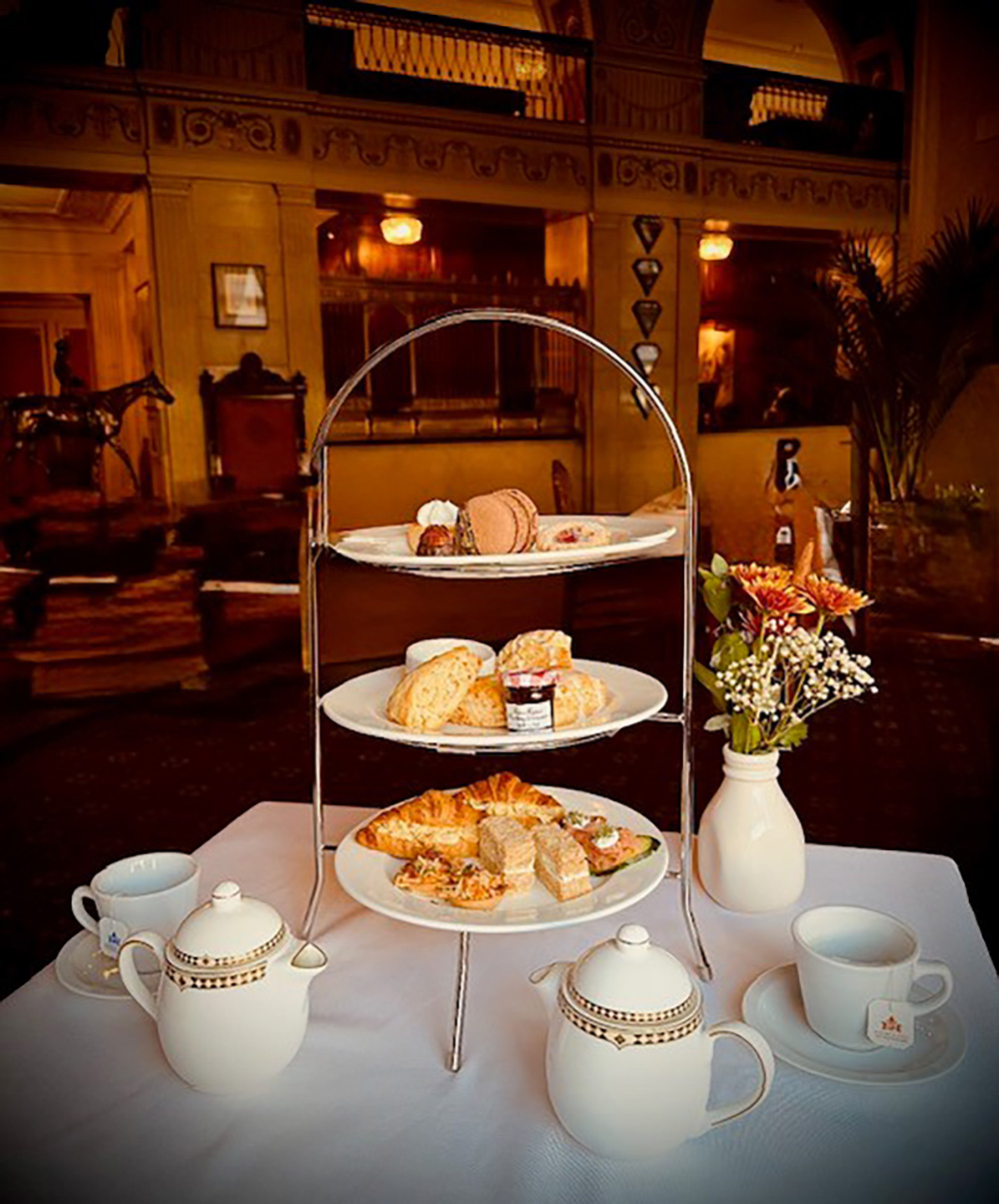 a three tiered tray with pastries and teapots on a table