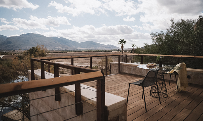 a deck with a table and chair and a table with a view of mountains
