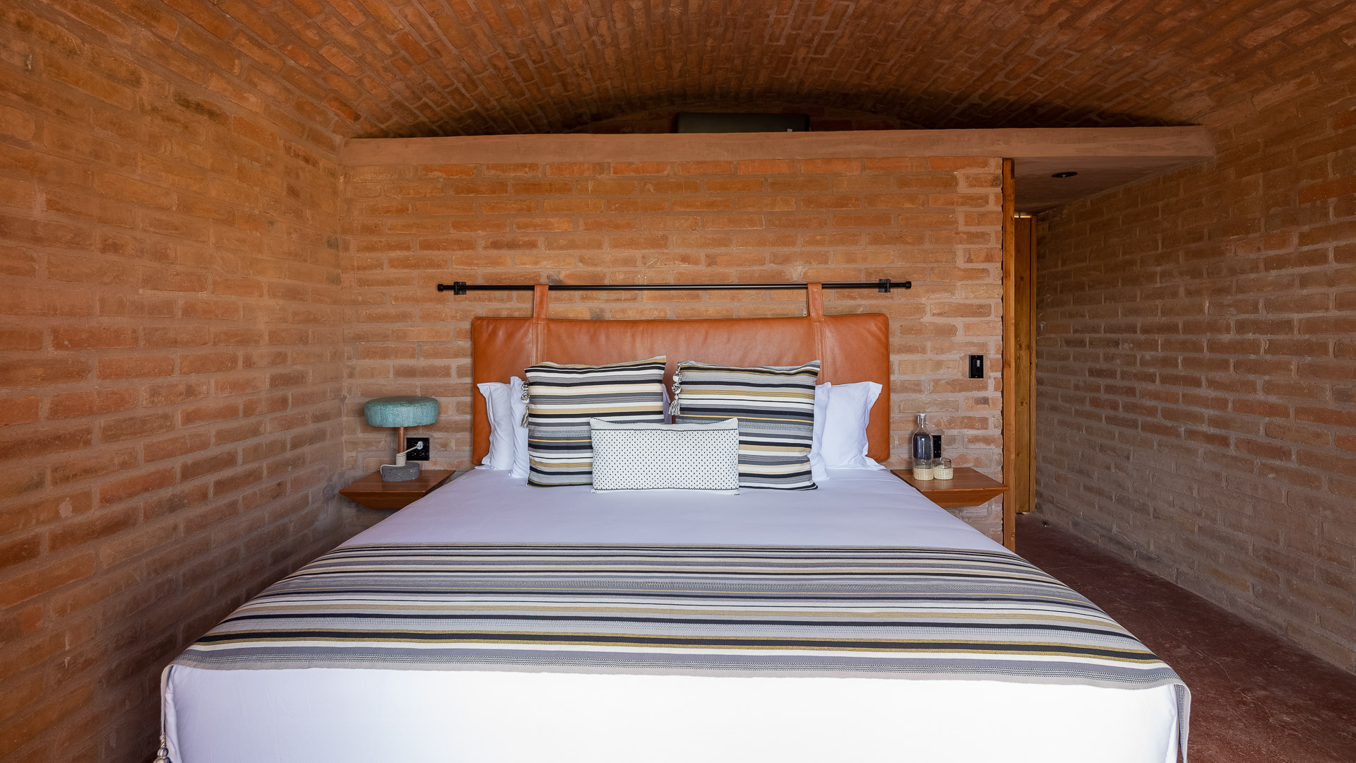 a bed with pillows and a brick wall