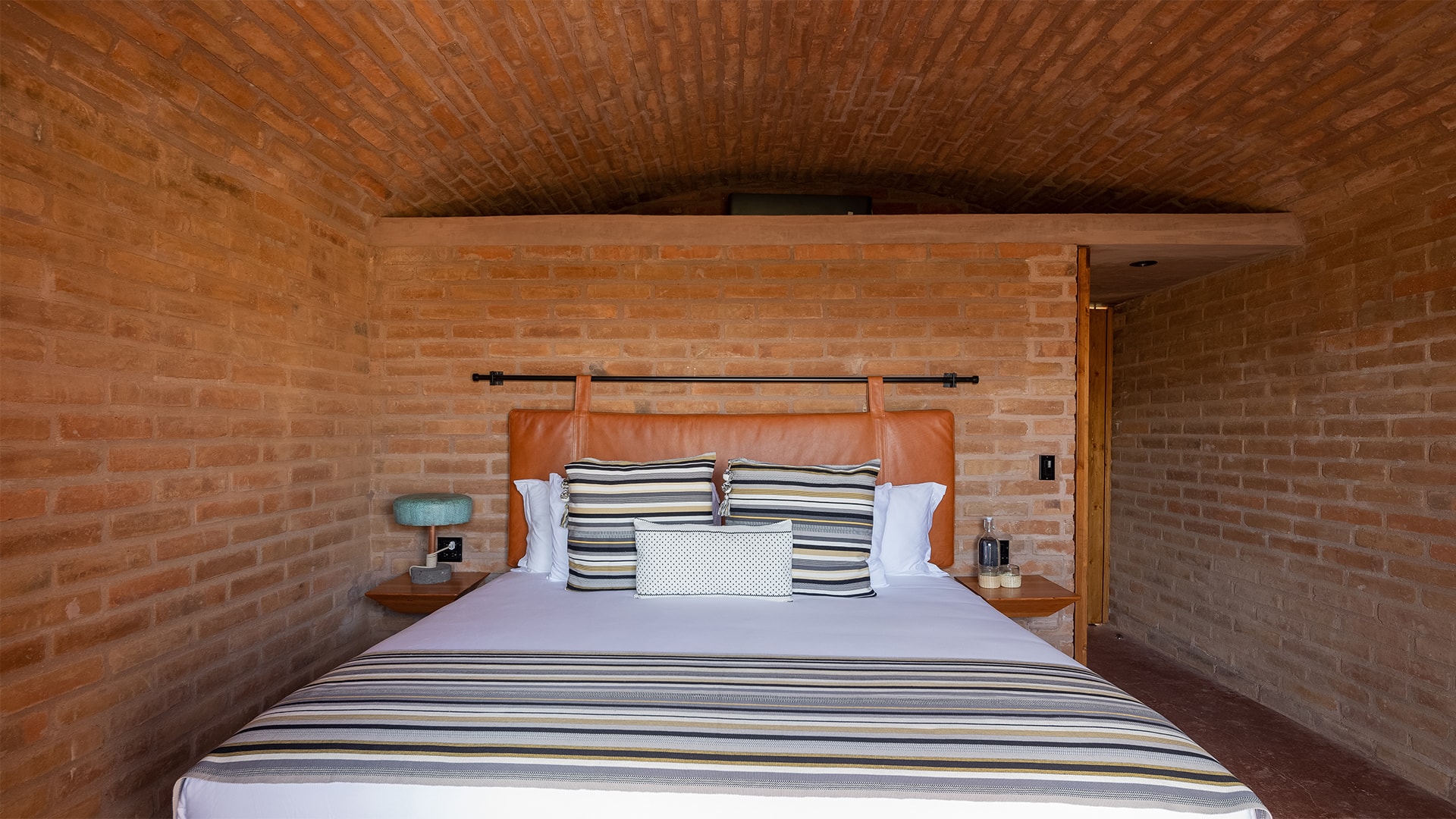 a bed with pillows in a room with brick walls