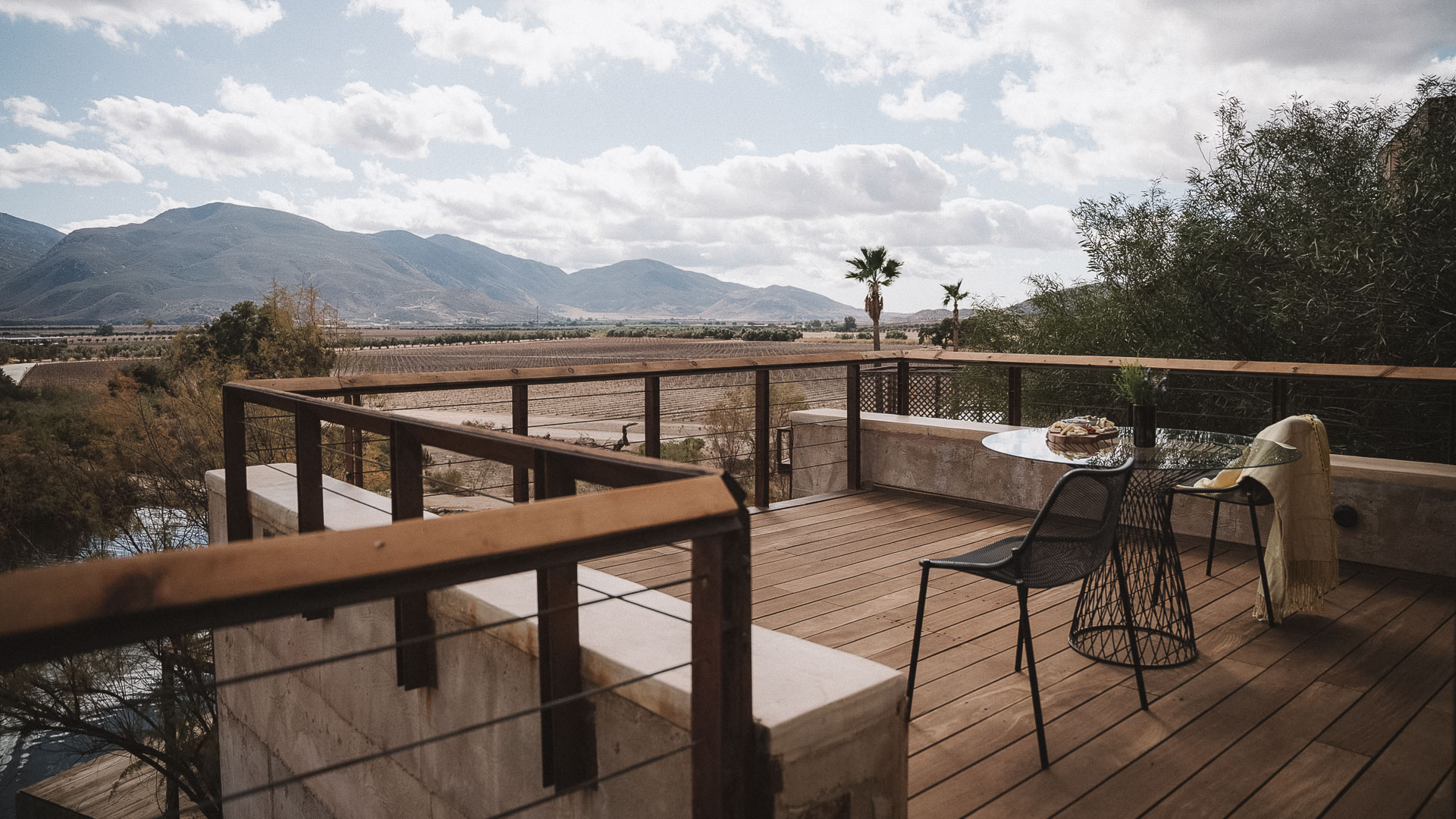 a deck with a table and chairs overlooking a valley