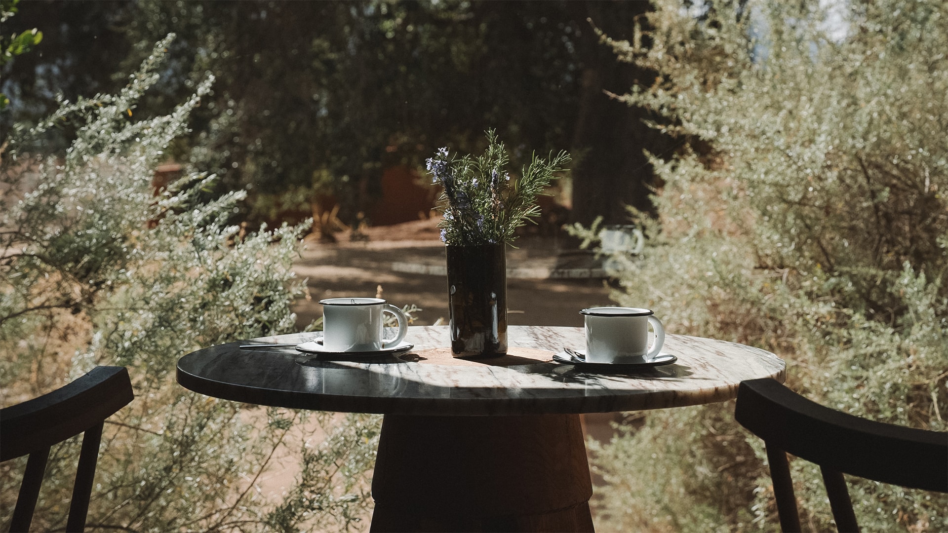 a table with two cups and a vase of flowers on it