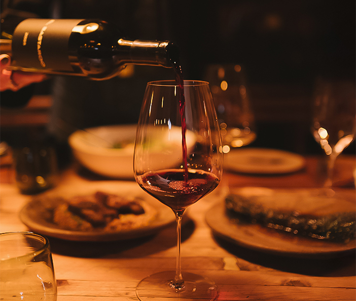 a person pouring wine into a glass