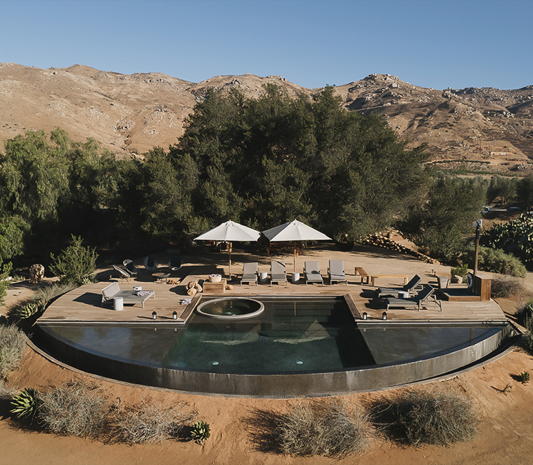 a pool with umbrellas and chairs in the middle of a desert