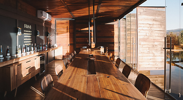 a long wooden table with chairs in a room with windows