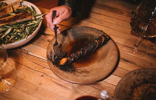 a hand holding a fork over a plate of food