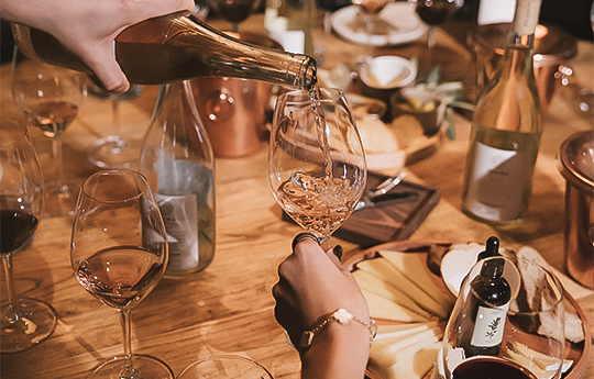 a person pouring wine into a glass