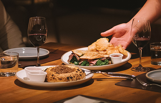 a hand reaching for food on a plate