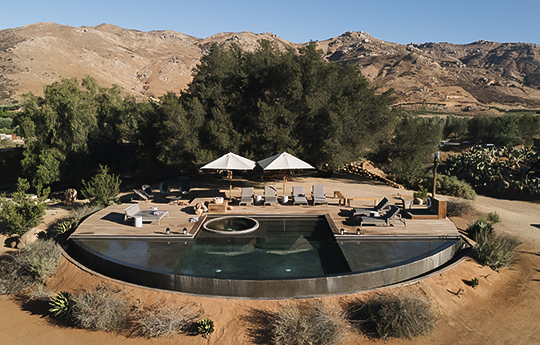 a pool with a hot tub and umbrellas in the desert