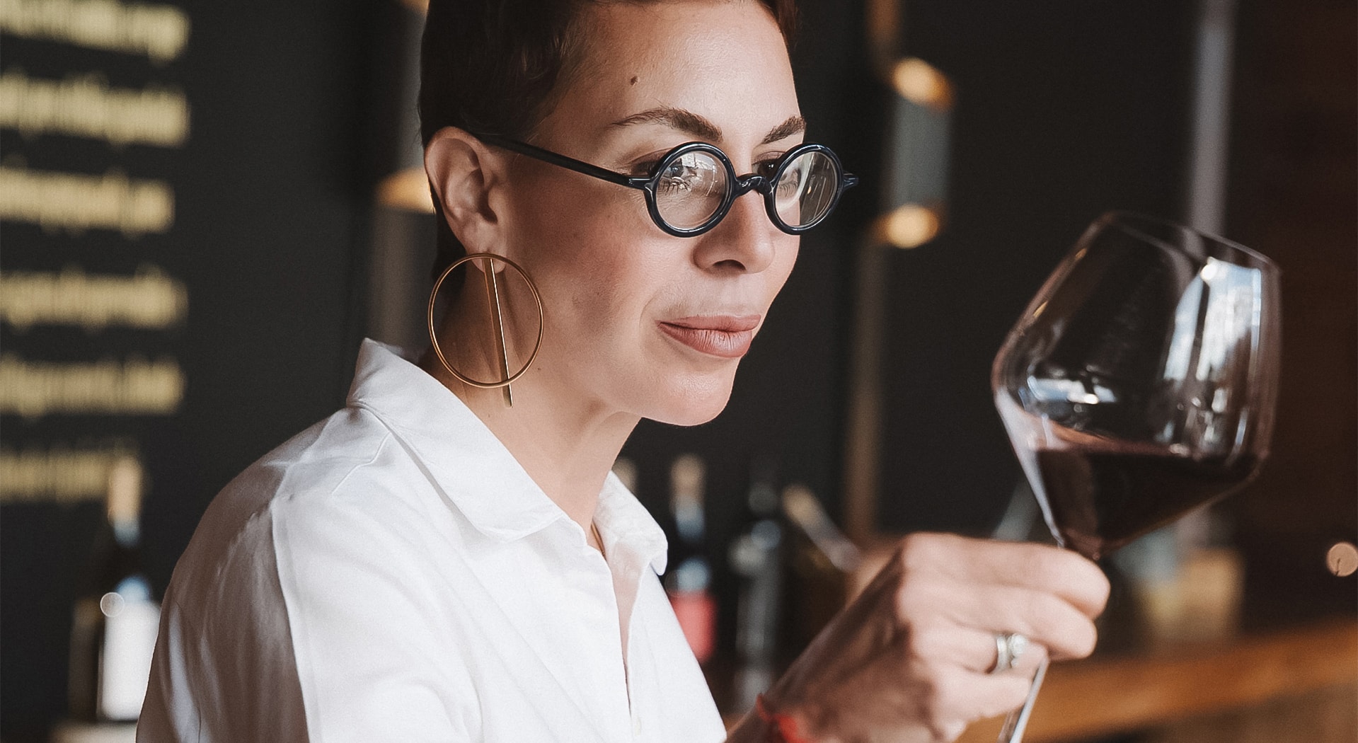 a woman wearing glasses and holding a glass