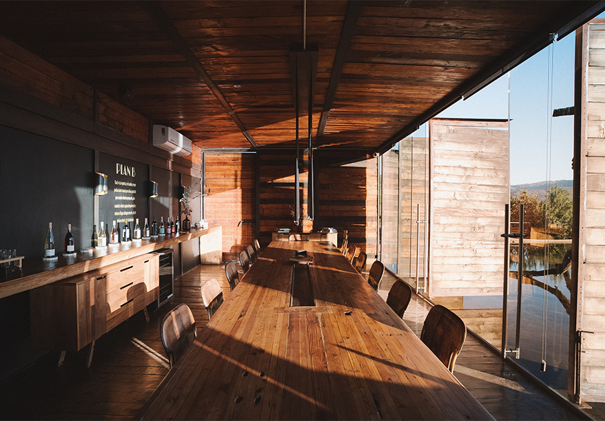 a long wooden table with chairs in a room with a window
