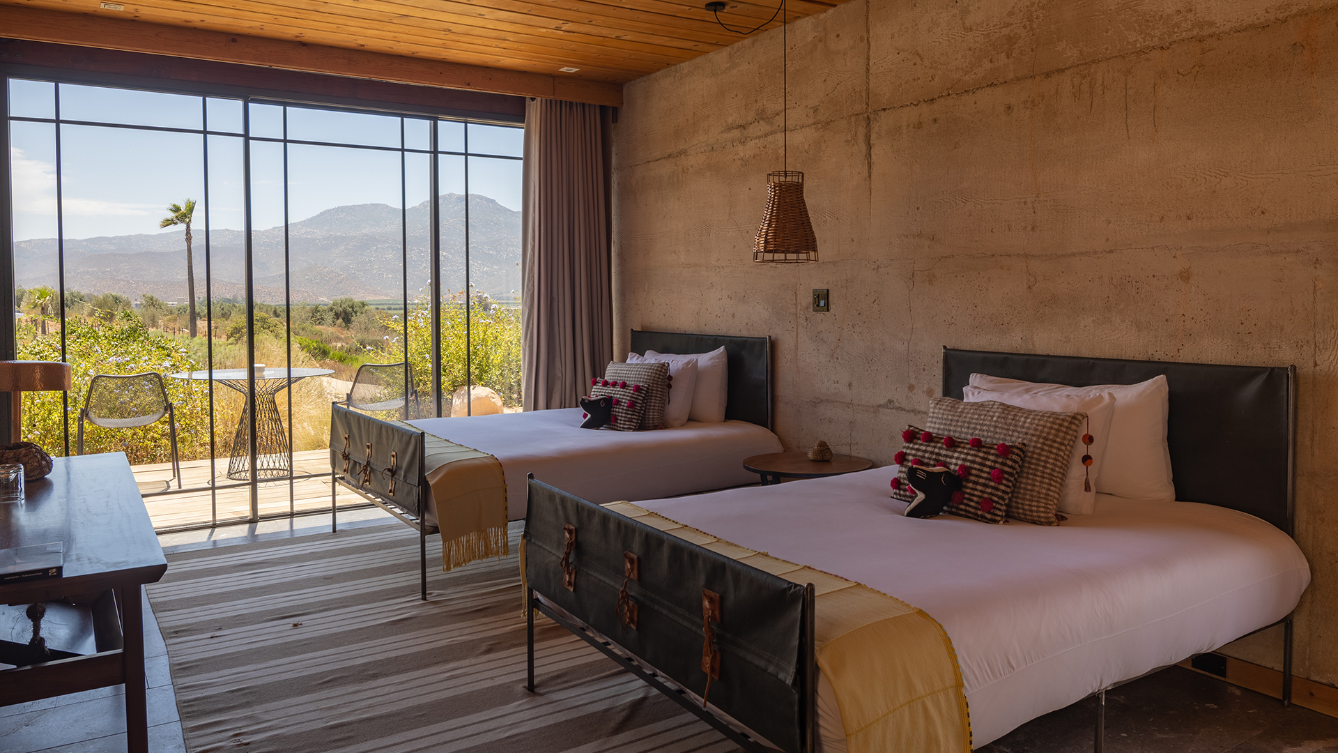 two beds in a room with a view of mountains and grass