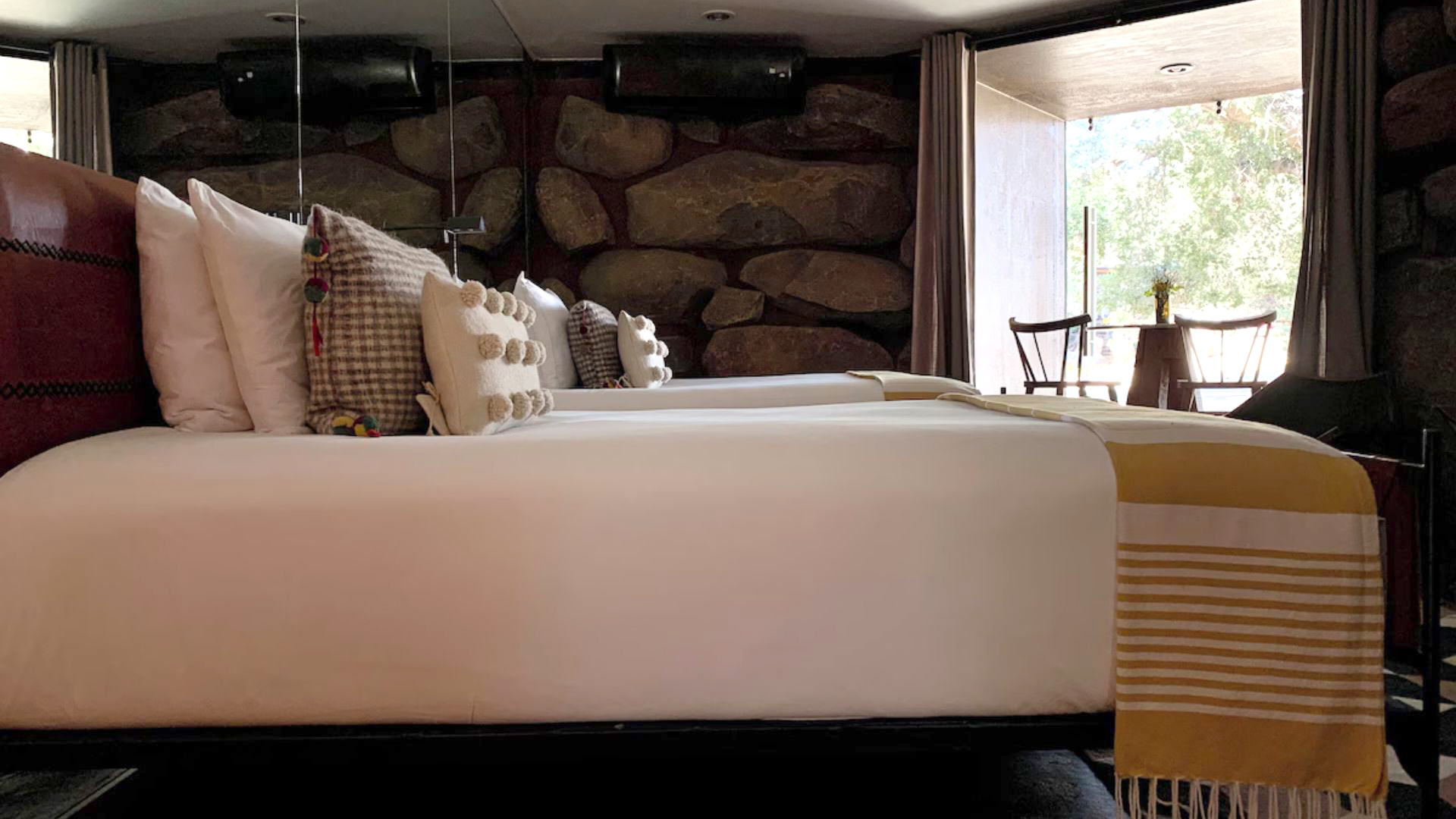 a bed with pillows and a table with a stone wall