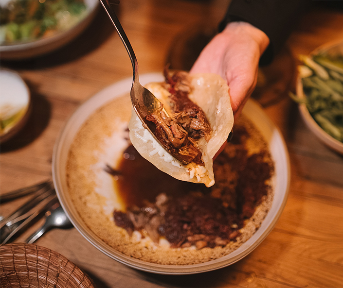 a person holding a fork over food