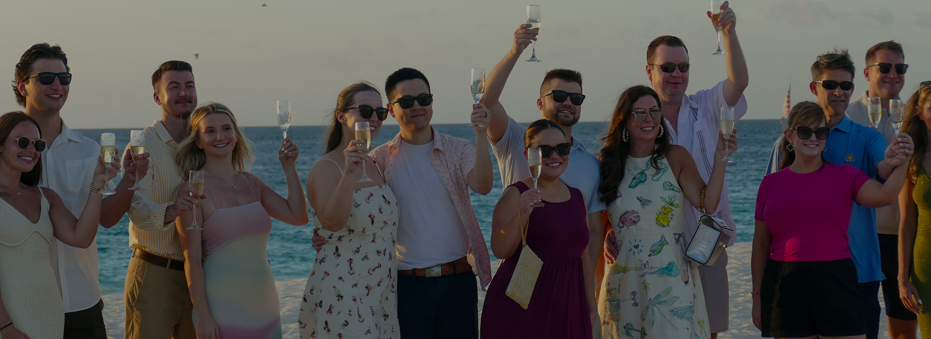 a group of people holding wine glasses on a beach