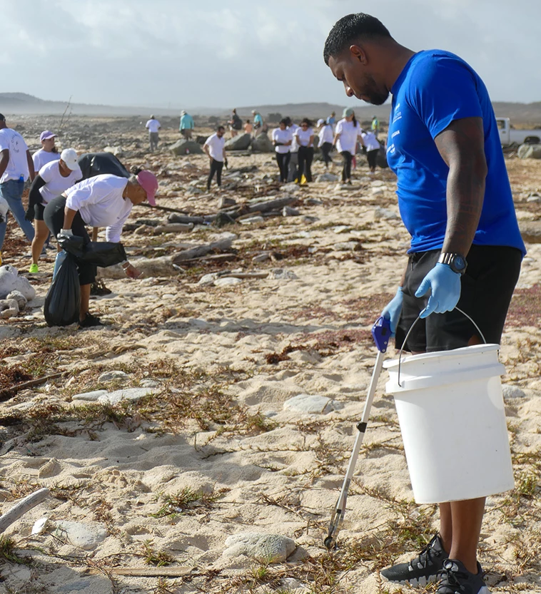a man holding a bucket and a stick on a beach