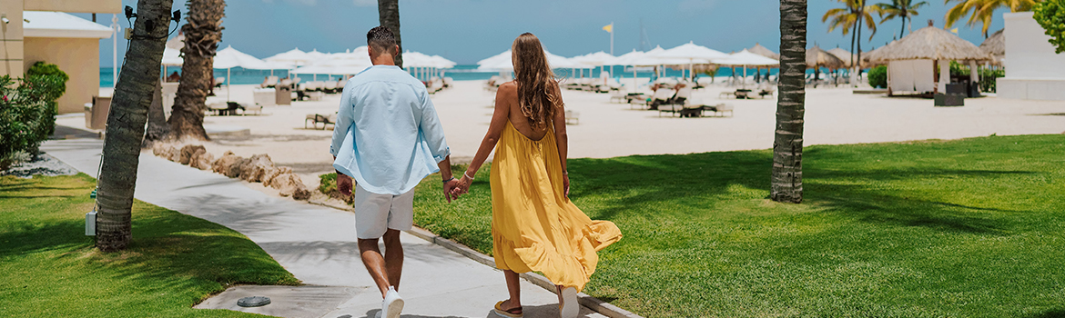 a man and woman holding hands walking on a sidewalk