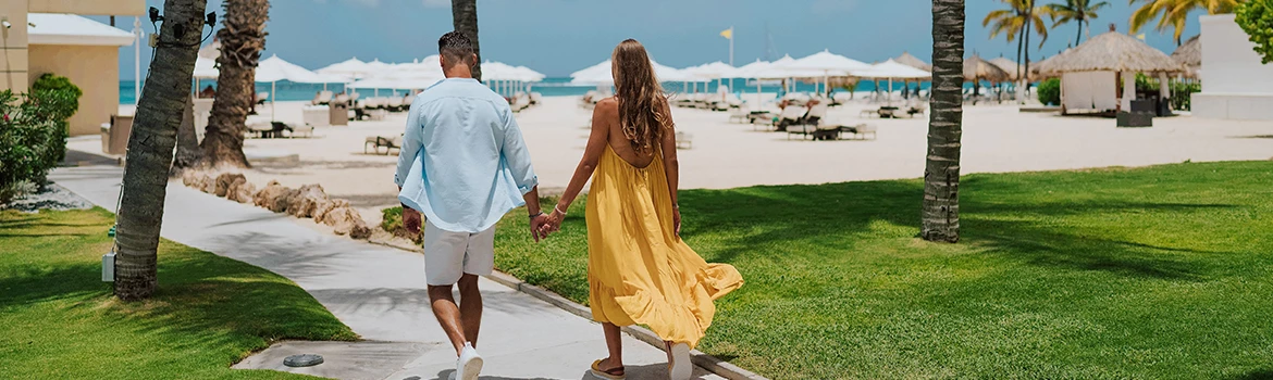 a man and woman holding hands walking on a sidewalk