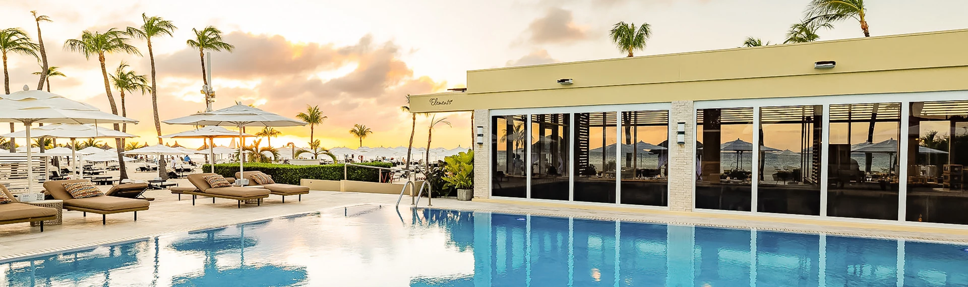 a pool with a building and a beach in the background