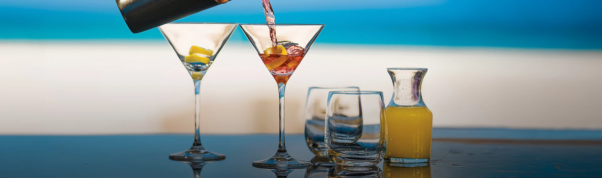 a person pouring a drink into a martini glass