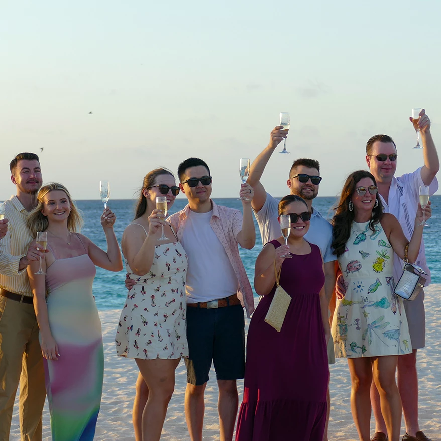 a group of people holding wine glasses on a beach