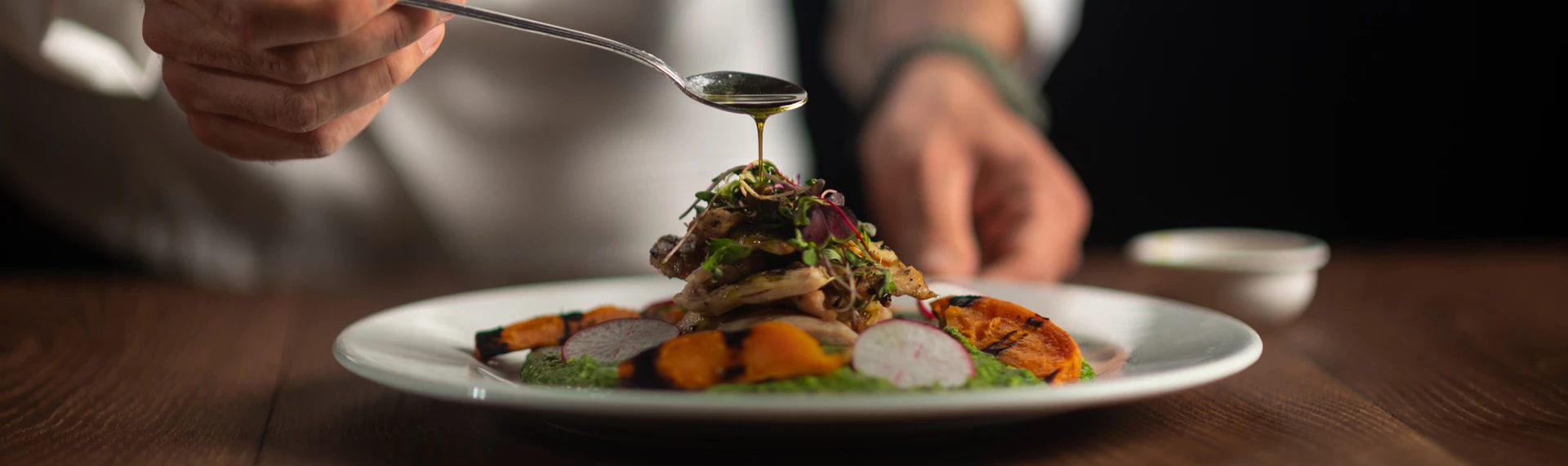 a spoon pouring a sauce onto a plate of food