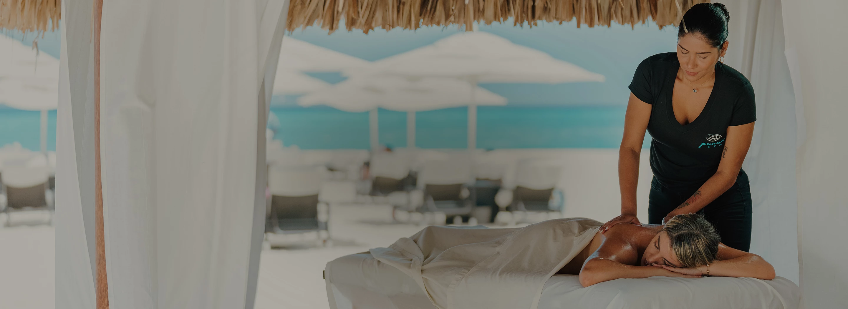 a person lying on a bed under a straw umbrella