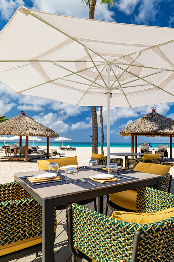a table set up on a beach with umbrellas and palm trees