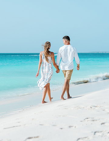 a man and woman holding hands on a beach
