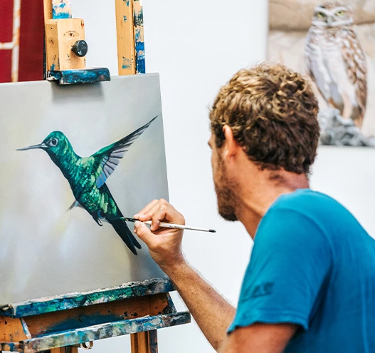 a man painting a bird on canvas