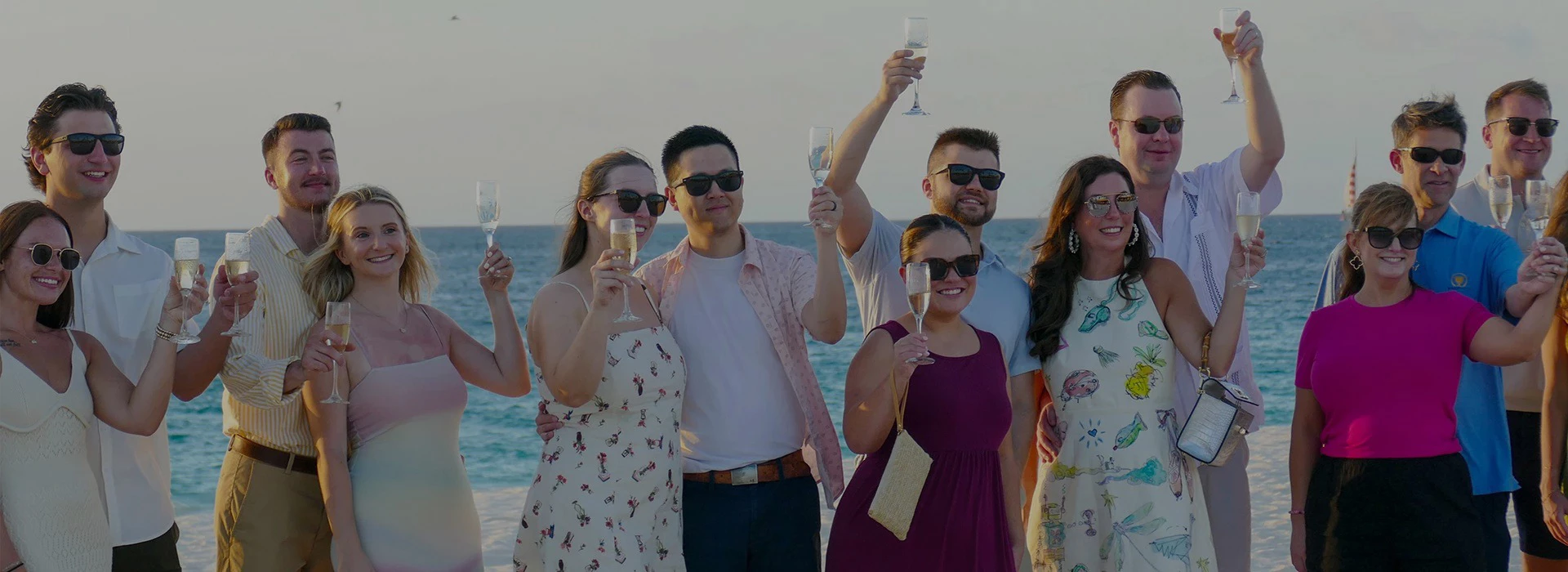 a group of people holding wine glasses on a beach