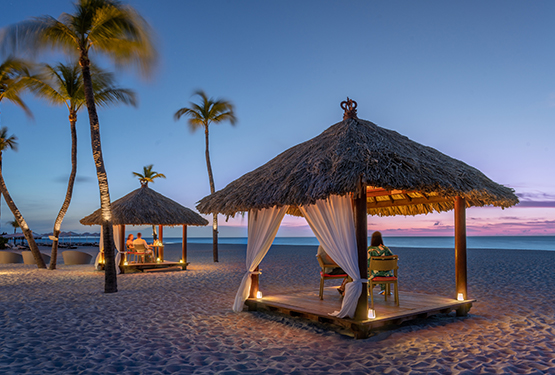 a group of people sitting in a hut on a beach